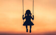 © nitnicha - A silhouetted girl on a swing during sunset, capturing the essence of childhood joy and freedom in a serene atmosphere.