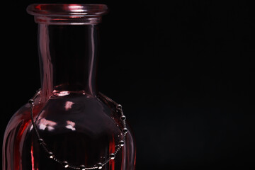 an elegant silver pendant hangs from a pink vase on a black background