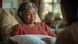 © keetazalay - An elderly woman receiving gentle care at home, with a nurse adjusting her pillows while discussing wellness plans