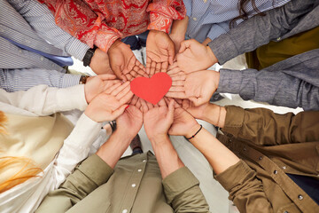 Top view of multiethnic people hands holding red paper heart symbol. Group of people standing in circle, promoting unity, love and support for World Organ Donation Day. Charity and altruism concept.