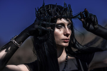 Goddess of death with black wings on a dried field