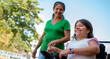 © Andrey - Grandmother and Granddaughter in Wheelchair Enjoying a Sunny Walk in City Park, Representing Disability Lifestyle