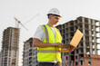 © Studio Peace - Architect works with a laptop on a construction site in a protective helmet and vest.