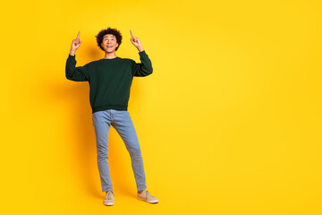 Wall Mural - Full body portrait of nice young man direct fingers up empty space wear sweater isolated on yellow color background