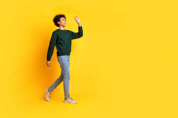 Poster - Full body portrait of nice young man walk wave empty space wear sweater isolated on yellow color background