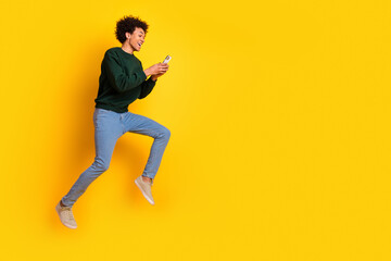 Sticker - Full body portrait of nice young man jump use phone empty space wear sweater isolated on yellow color background