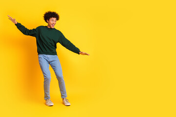 Wall Mural - Full body portrait of nice young man balancing empty space wear sweater isolated on yellow color background