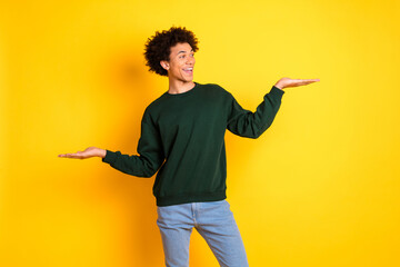 Wall Mural - Portrait of nice young hold empty space man wear sweater isolated on yellow color background