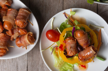 Bacon Wrapped Sausage With fresh vegetables of various colors on white plate, top view