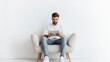 © ibooM - A man in casual attire wearing sneakers, sitting on a small one-seater sofa, using a tablet, set against a clean white background,