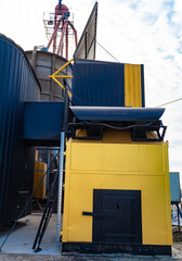 Industrial building with yellow and black exterior in coastal setting. A tall industrial structure features a yellow and black exterior, situated near the coast