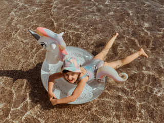 child girl swimming on inflatable ring in the form of a unicorn top view