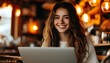 © 杜克 杜 - Cheerful woman with wavy hair focused on laptop in a welcoming cafe surrounded by warm lighting