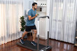 © InfiniteFlow - Athletic and sporty man running on running machine during home body workout exercise session for fit physique and healthy sport lifestyle at home. Gaiety home exercise workout training.