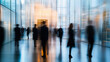 © Elmin - A blurry photo shows people in suits and dresses standing in the lobby of a sleek, modern office building.