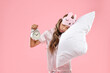 © New Africa - Overslept girl with sleep mask, pillow and alarm clock on pink background