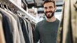 © Bonsales - Bearded young man with a joyful smile exploring a vibrant clothing rack in a trendy retail store, discovering stylish outfits.