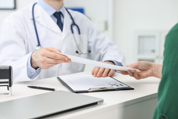 Wall Mural - Doctor giving prescription to patient at white table in clinic, closeup