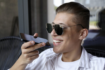 Poster - Young man recording voice message via smartphone in outdoor cafe