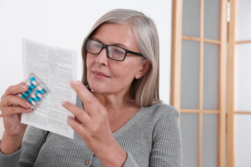 Wall Mural - Senior woman with pills reading medicine instruction at home