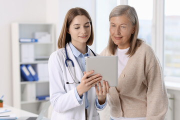 Canvas Print - Smiling healthcare worker and senior patient checking analysis results on tablet in hospital