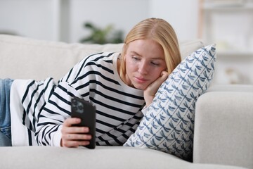 Sticker - Beautiful woman using smartphone on sofa indoors