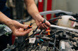 © dikushin - Closeup hands of experienced car electrician mechanic male working with electric block in car, servicing engine in automobile repair and renew service station. Repairman examining broken engine.