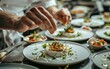 © Artsaba Family - A chef's precise hands adorn a starter dish with fresh herbs in the dynamic setting of a high-end restaurant kitchen.