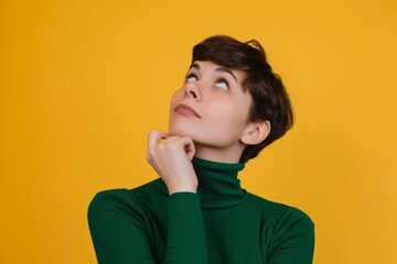 A thoughtful woman with a stylish short hairstyle contemplating ideas while gazing upwards against a vibrant yellow background