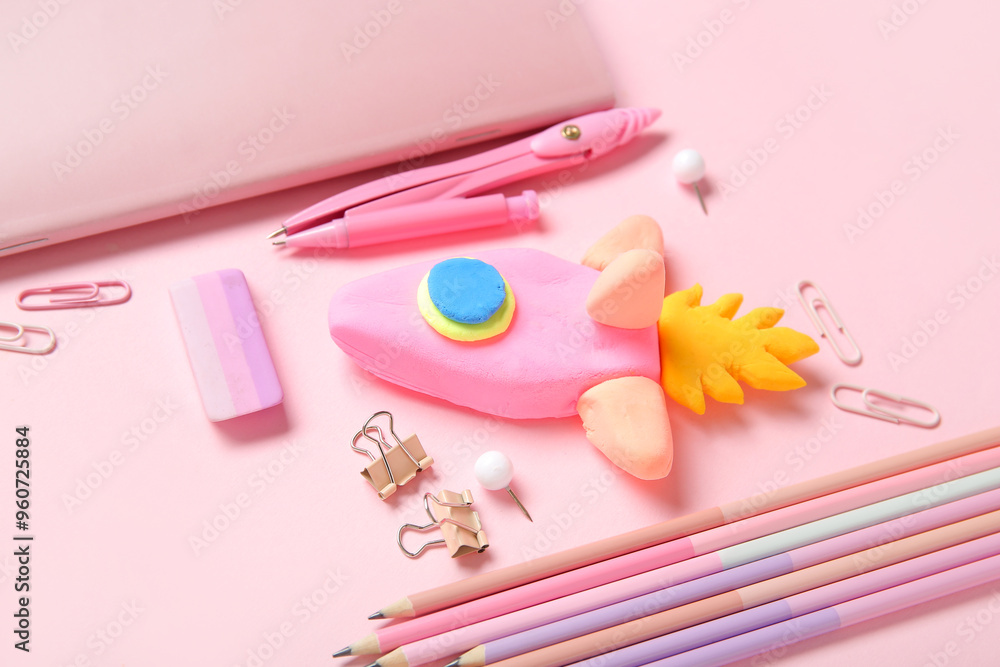 Rocket made of plasticine with different stationery on pink background