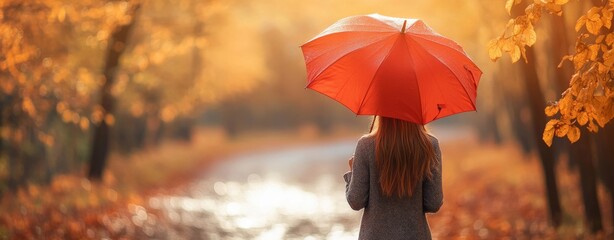 Wall Mural - A young woman spins while holding an umbrella in an autumn park, a yellow October park with autumn leaves, an autumn stroll in the park with an umbrella