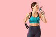 © Pixel-Shot - Sporty young woman with jumping rope drinking water on pink background