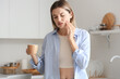 © Pixel-Shot - Young woman with cup of hot coffee suffering from tooth ache at home