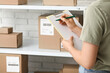 © Pixel-Shot - Woman writing in clipboard at postal warehouse, closeup
