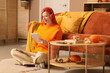 © Pixel-Shot - Beautiful young happy woman in headphones with autumn decor and tablet sitting on floor at home