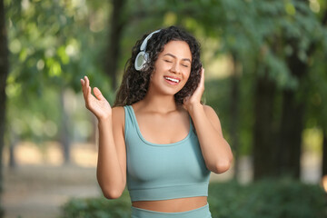 Poster - Sporty young African-American woman in headphones in park