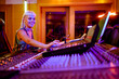 © Zamrznuti tonovi - Blonde woman sound engineer working at the soundboard in her music studio