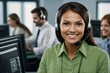 © Peidrow - Green dressed brunette young woman with a headset smiling, working as a call center operator in a busy office. Bussineswoman, representative, operator, assists with customer support and communication
