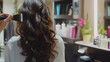 © Ratchadaporn - A stylist is curling beautiful hair in a modern salon. The rich curls enhance the glamour and elegance of the look.