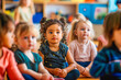 © MVProductions - Group of small nursery school children sitting and listening to teacher on floor indoors in classroom.