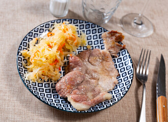 Wall Mural - Juicy pork steak with sauerkraut on the dinner table