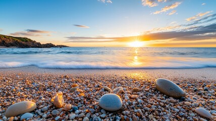 The beach is covered in small rocks and the sun is setting in the distance