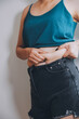 © ARMMY PICCA - fat woman, fat belly, chubby, obese woman hand holding excessive belly fat with measure tape, woman diet lifestyle concept