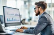 © Wan - A man working on a computer, analyzing data in a modern office environment.