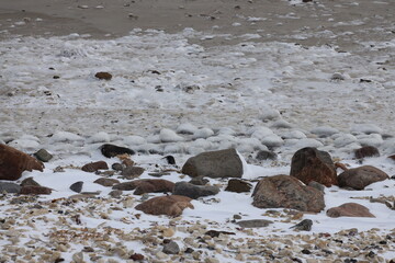 rocky sub-arctic shoreline with ice-covered rocks from wave action