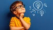 © K-MookPan - Curious boy in glasses thinking creatively, with lightbulbs drawn on the wall, signifying ideas and imagination.