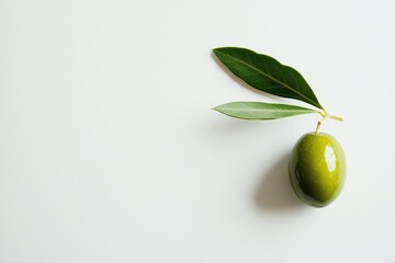 A green olive with leaves on a white background, showcasing its natural beauty.