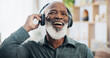 © Azee Jacobs/peopleimages.com - Senior man, headphones and retirement for music, relax and positive mood on weekend with radio in house. Black person, listening and happy in living room for podcast, streaming or jazz with happiness
