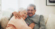 © peopleimages.com - Hug, relax and senior couple in house, love and care with retirement, happiness and bonding together. Apartment, embrace and mature woman with elderly man on sofa, support and comfortable in lounge