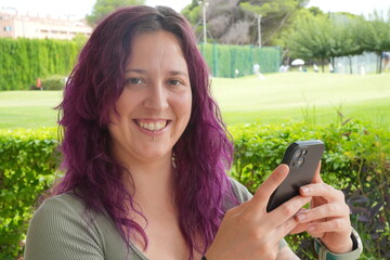 Wall Mural - A woman with purple hair is holding a cell phone and smiling